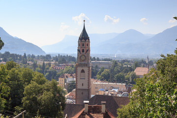 The spire of the church St. Nikolaus and Merano panorama with mountains, South Tyrol, Italy - obrazy, fototapety, plakaty