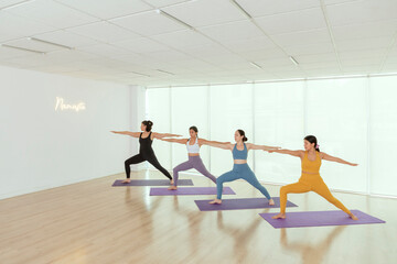 Naklejka premium group of women doing the warrior pose while practicing yoga in a studio