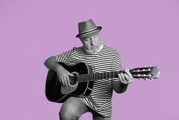 An elderly man plays the acoustic guitar. Striped t-shirt, straw hat on a dark pink background....
