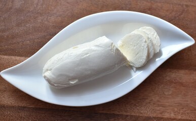 Fototapeta na wymiar mozzarella cheese on a white plate on a wooden table