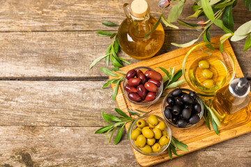 Green, black and red olives with leaves in bowls on a textured old wood background. Delicious and healthy food. Delicacy.Mediterranean Kitchen. Place for text. copyspace.