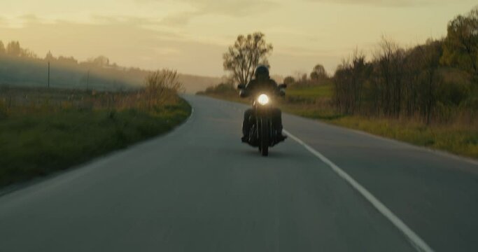 Shaky shot of a man riding a motorcycle through an empty road.