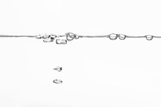 schwungvolle Wasseroberfläche mit Wellen und Wirbel auf weißem Hintergrund künstlerische Darstellung von Luftblasen die eine Wasseroberfläche durchbrechen