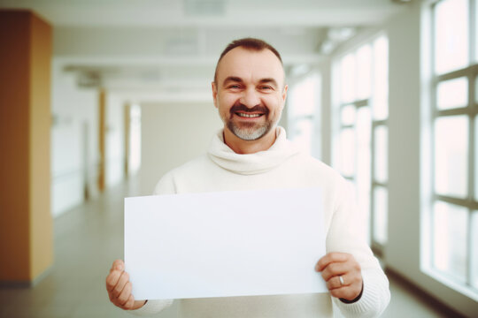 Portrait of happy senior man holding blank sheet of paper in office