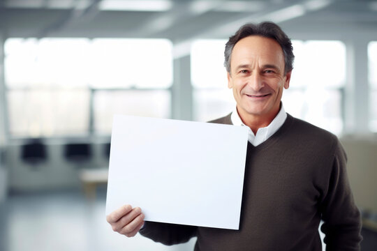 Handsome mature man holding a blank sheet of paper in an office