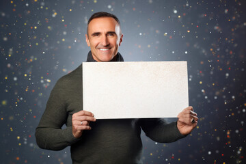 Handsome young man holding a white sheet of paper on a blue background
