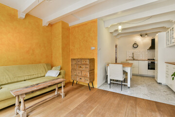 a living room with orange walls and wood flooring in the center of the room there is a green couch