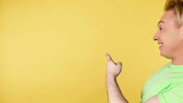 Face, man and pointing to mockup, advertising, branding in studio isolated on yellow background. Smiling guy male showing product placement, empty place or mock up space, marketing in green t-shirt
