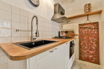 a kitchen with white tiles and wooden counter tops on the wall above it is a clock hanging over the sink