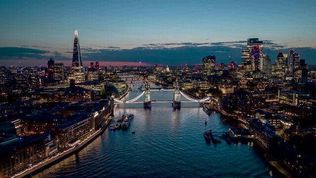 Aerial hyper lapse view of the famous Tower Bridge and river Thames with the illuminated City skyscrapers during night time, England