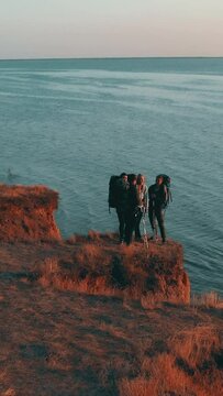 The four travelers stand on the mountain top on the seascape background