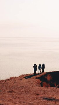 The four tourists with backpacks walking on the seascape