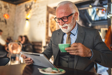 Senior man businessman business owner use digital tablet sit at cafe