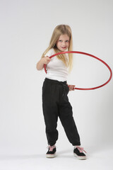 Studio portrait of beautiful cheerful little girl playing with red hula hoop