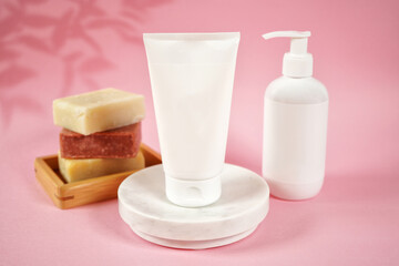Cosmetic skincare blank container mockups in a styled setting. Pink background with leaves shadow photography. 