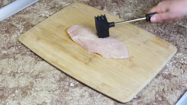 Tenderizing chicken breast with meat mallet or tenderizer hammer tool.