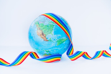 Earth globe model with LGBT colorful rainbow ribbon on the white background. LGBTQIA Pride Month...