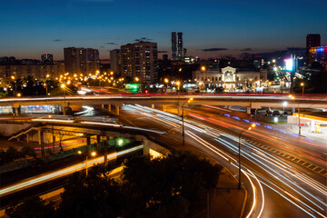 Fototapeta na wymiar City highway traffic - street with fast moving cars and lights trails - long exposure. Warm illumination at night. Rush hour, urban, transportation and city life concept