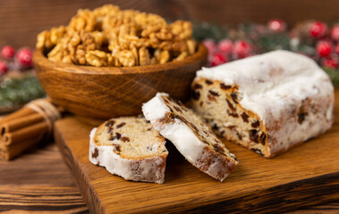 Christmas stollen on a texture table. Traditional German Christmas dessert cut into pieces. Cake with nuts, cinnamon, raisins, dried fruits and marzipan. baking for christmas. Place for text. 