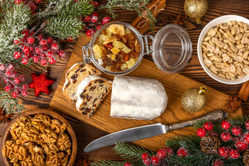 Christmas stollen on a texture table. Traditional German Christmas dessert cut into pieces. Cake with nuts, cinnamon, raisins, dried fruits and marzipan. baking for christmas. Place for text. 