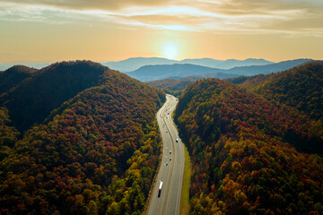 View from above of I-40 freeway route in North Carolina leading to Asheville thru Appalachian mountains with yellow fall woods and fast moving trucks and cars. Interstate transportation concept