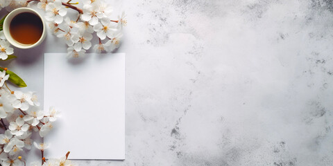 Marble and flower background with copy space. Cup of coffee, sakura and blank paper on light grey stone