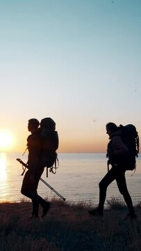 The group of travelers with backpacks walking near the sea. slow motion