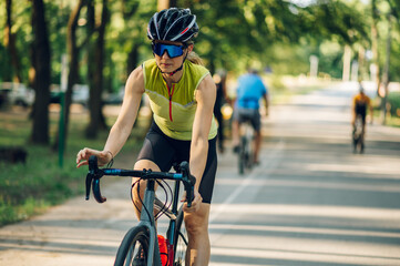Fototapeta na wymiar Portrait of a woman riding a bike during a sport cycling race on a sunset
