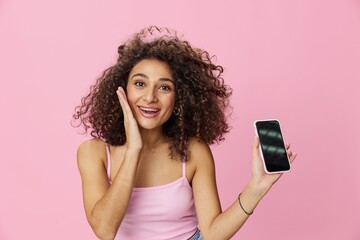 Woman blogger holding phone video call takes selfies, with curly hair in pink smile t-shirt and...