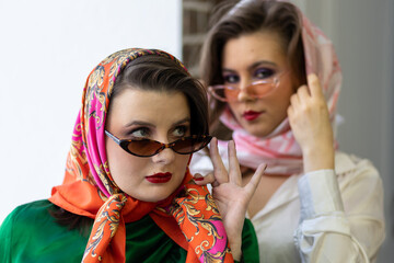 Two best friends, young girls dressed in retro vintage style with bright trendy make up of eighties...