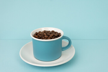 Coffee beans in blue cup on blue background 