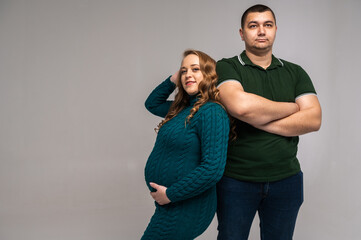 Fototapeta premium Image of happy young man standing with his pregnant wife isolated on white wall background. Growing a family, expecting a child, a young family, emotions