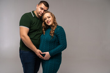 Image of happy young man standing with his pregnant wife isolated on white wall background. Growing a family, expecting a child, a young family, emotions