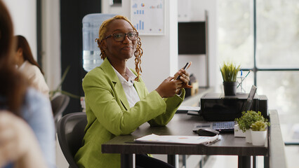 African american worker using smartphone app on break, checking social media website. Executive...