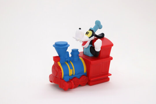 Happy Goofy in Disneyland attraction. Goffy driving a train in the Disney parks. Disney franchise collectible toy on isolated white background. 