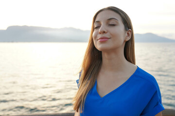 Attractive young woman breathing with closed eyes on sunset seascape