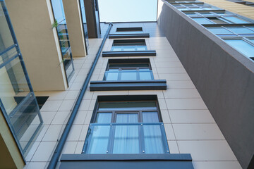 Obraz premium Modern multi-storey house in a new residential complex against the blue sky. The concept of mortgage housing lending and a happy family life. Beautiful multicolored house in the city