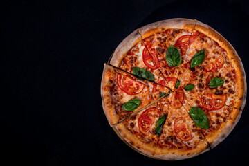 Delicious fragrant pizza-Margherita with mozzarella, tomatoes and basil on tomato sauce on black...