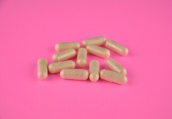 A bunch of vitamin pills (capsules) on a neon pink background