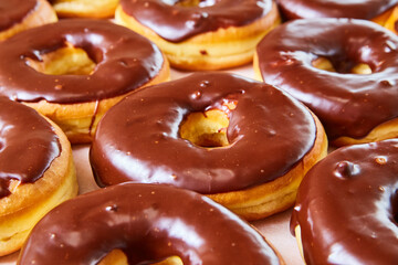 Side shot of half glazed yeast donuts with chocolate frosting on white tray background
