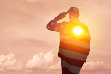 Silhouette of soldier with print of sunset and USA flag saluting on a background of light sky....