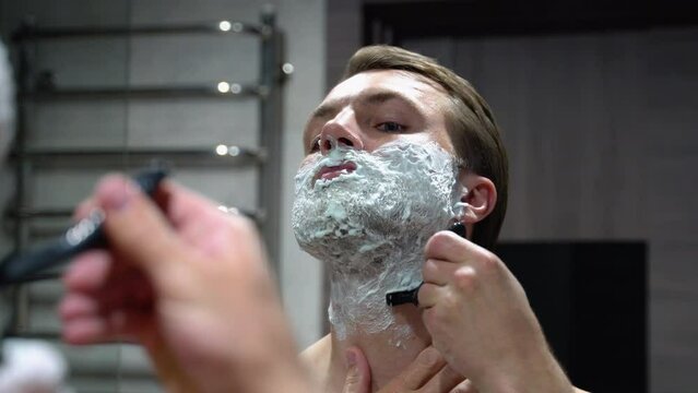 Handsome man shaving his beard in bathroom