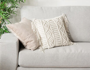 a gray couch with some pillows sitting on it and a plant