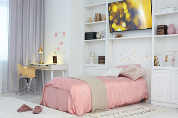 Stylish teenager's room interior with comfortable bed, workplace and modern TV set