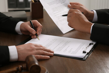 Law and justice. Lawyers working with documents at wooden table, closeup