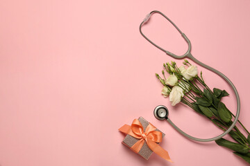 Stethoscope, gift box and eustoma flowers on pink background, flat lay with space for text. Happy Doctor's Day