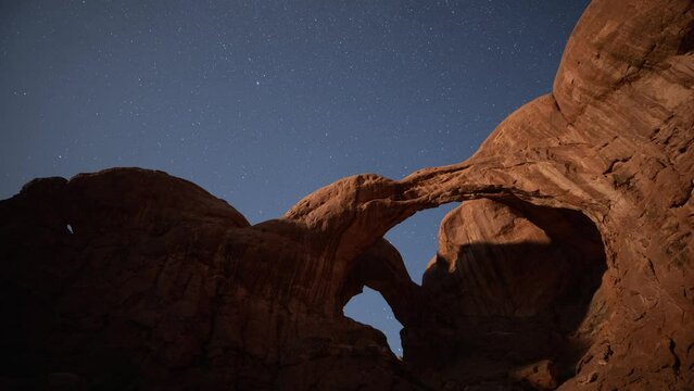 Time lapse of the night sky rotating behind the Double Arch in Arches National Park in Utah