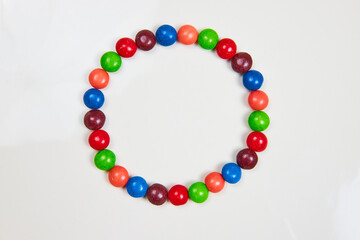 Skittles sugar candy in a circle with variety of colors from red and blue and violet and purple and orange and green on a white background
