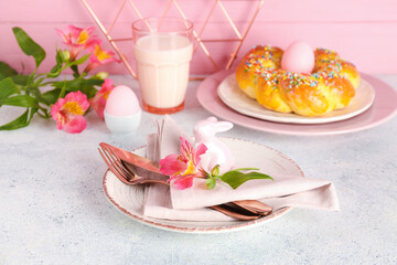 Beautiful table setting with tasty Italian Easter bread, glass of milk and alstroemeria flowers on light table