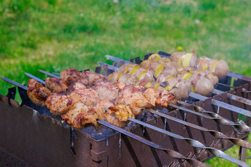 Kebabs are grilled in portable metal brazier with potatoes and bacon